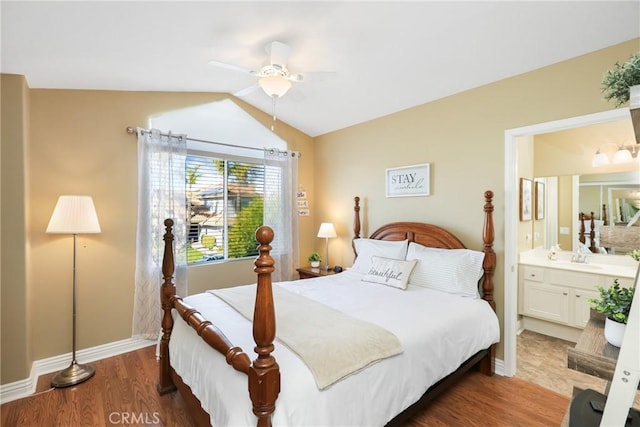 bedroom with lofted ceiling, ensuite bath, baseboards, and wood finished floors