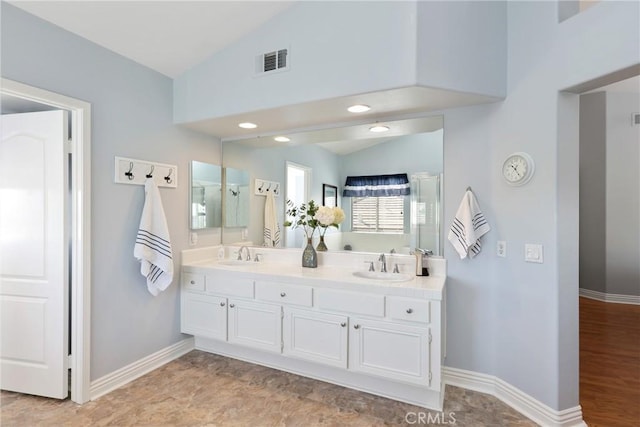 bathroom featuring lofted ceiling, a sink, and visible vents