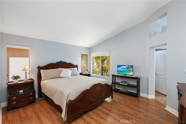 bedroom featuring lofted ceiling, baseboards, and wood finished floors