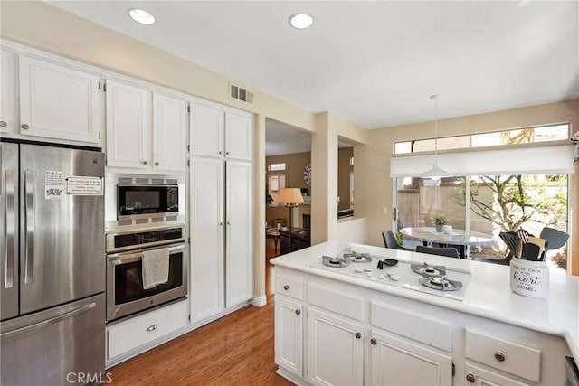 kitchen featuring visible vents, white cabinetry, light countertops, appliances with stainless steel finishes, and light wood finished floors