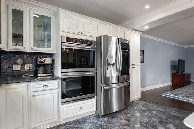 kitchen with white cabinetry, baseboards, ornamental molding, appliances with stainless steel finishes, and glass insert cabinets