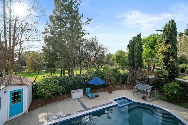 outdoor pool featuring an outbuilding, a patio area, and an in ground hot tub