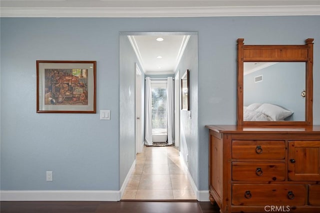 corridor with light tile patterned floors, baseboards, and crown molding