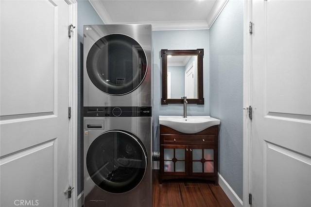 laundry area with ornamental molding, laundry area, a sink, and stacked washing maching and dryer