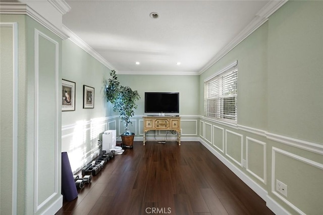 unfurnished living room with crown molding, dark wood finished floors, recessed lighting, a decorative wall, and wainscoting