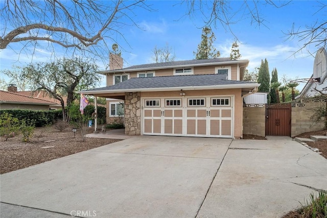 view of front facade featuring a chimney, a gate, a garage, stone siding, and driveway