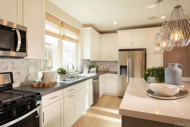 kitchen featuring a sink, white cabinetry, appliances with stainless steel finishes, decorative light fixtures, and an inviting chandelier