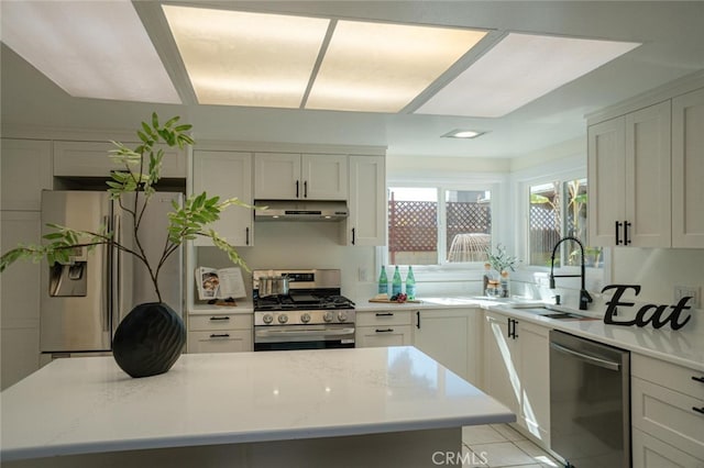 kitchen with appliances with stainless steel finishes, white cabinets, a sink, and under cabinet range hood