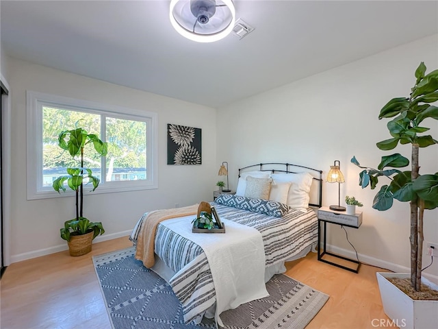 bedroom featuring light wood-type flooring, visible vents, and baseboards