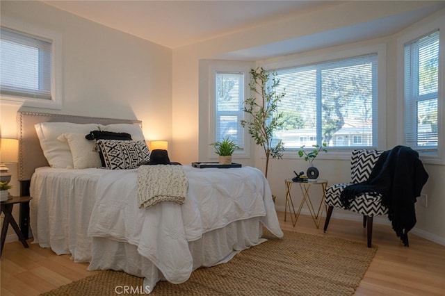 bedroom with multiple windows, light wood-style flooring, and baseboards