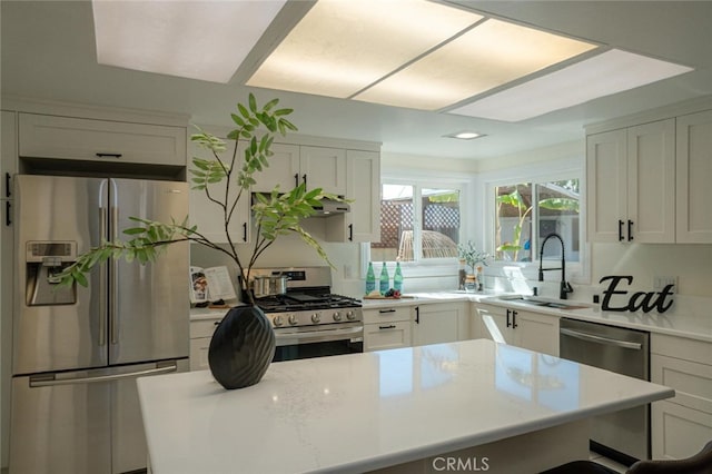 kitchen featuring stainless steel appliances, a sink, white cabinetry, and a center island