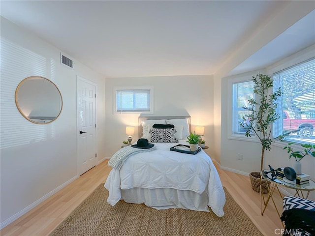 bedroom with light wood finished floors, baseboards, and visible vents