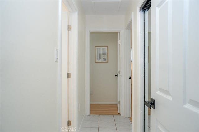 hallway with attic access and light tile patterned floors