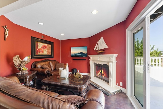 living area featuring a glass covered fireplace, baseboards, recessed lighting, and wood finished floors