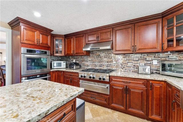 kitchen with tasteful backsplash, a toaster, stainless steel appliances, under cabinet range hood, and a warming drawer