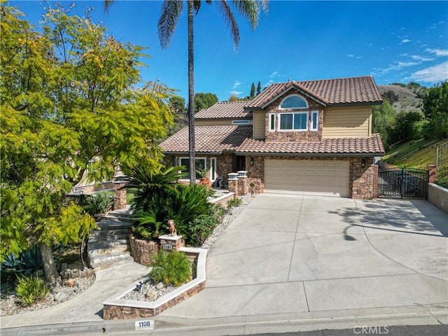 view of front of property featuring a tile roof, an attached garage, fence, stone siding, and driveway