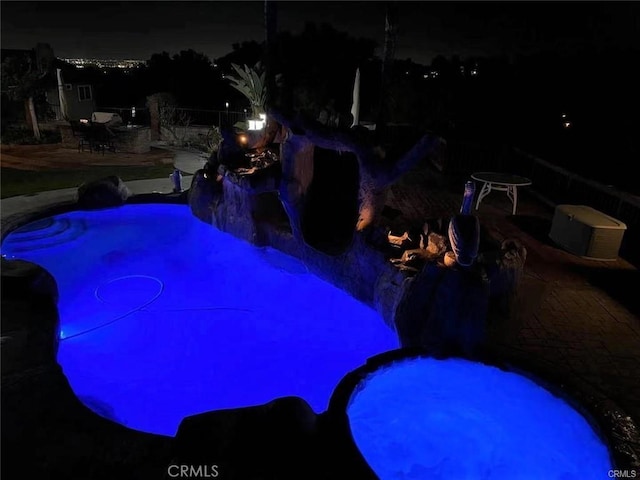 pool at night featuring an outdoor pool and a patio