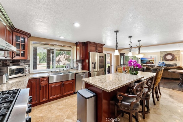 kitchen with light stone counters, tasteful backsplash, appliances with stainless steel finishes, open floor plan, and a sink