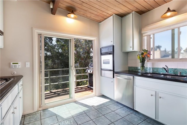 kitchen with stainless steel appliances, a sink, a healthy amount of sunlight, tasteful backsplash, and dark countertops