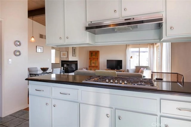 kitchen with visible vents, dark countertops, under cabinet range hood, stainless steel gas stovetop, and white cabinetry