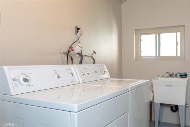 clothes washing area featuring laundry area, separate washer and dryer, and a sink