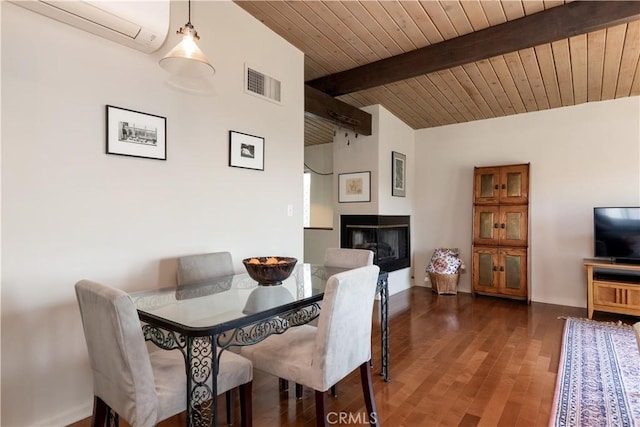 dining space featuring visible vents, wood finished floors, vaulted ceiling with beams, a fireplace, and a wall mounted AC