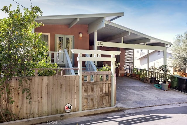 view of front facade featuring french doors, fence, and stucco siding