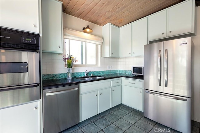 kitchen featuring dark countertops, decorative backsplash, stainless steel appliances, and a sink