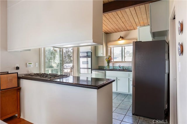 kitchen with dark countertops, decorative backsplash, appliances with stainless steel finishes, white cabinets, and a sink