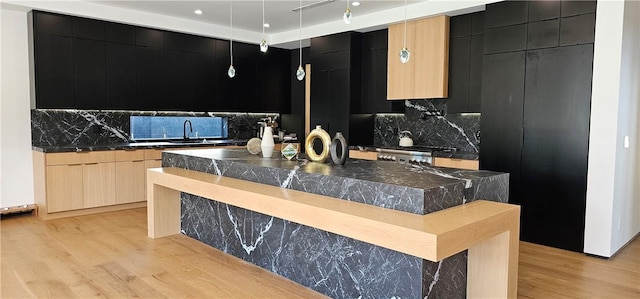 kitchen featuring dark countertops, dark cabinetry, a sink, and modern cabinets