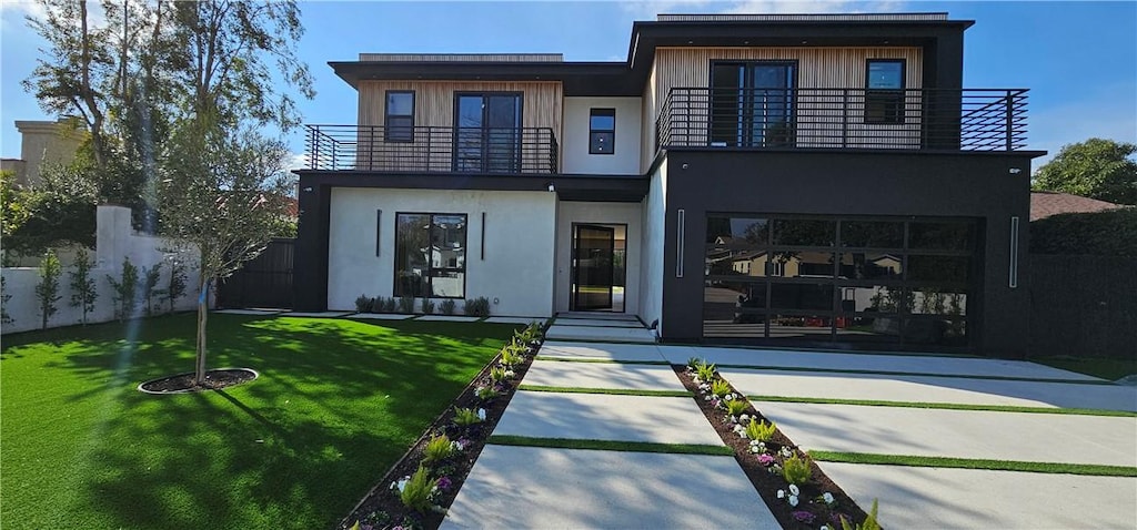 back of property with a lawn, fence, a balcony, and stucco siding