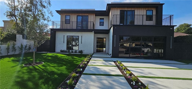 back of property with a lawn, fence, a balcony, and stucco siding