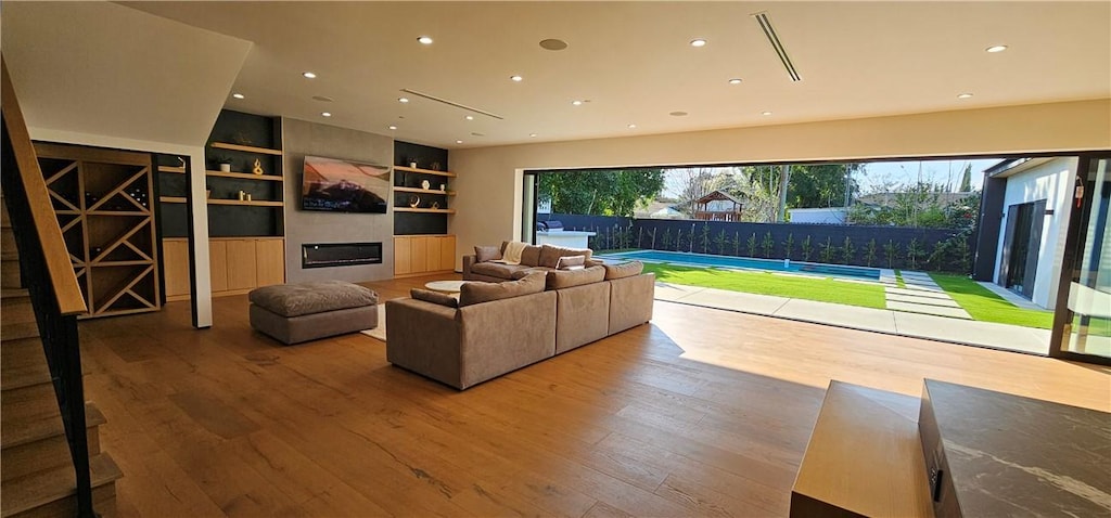 living room featuring a large fireplace, recessed lighting, wood finished floors, and a healthy amount of sunlight