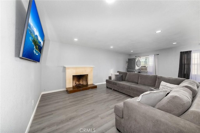 living room with recessed lighting, a fireplace with raised hearth, baseboards, and wood finished floors