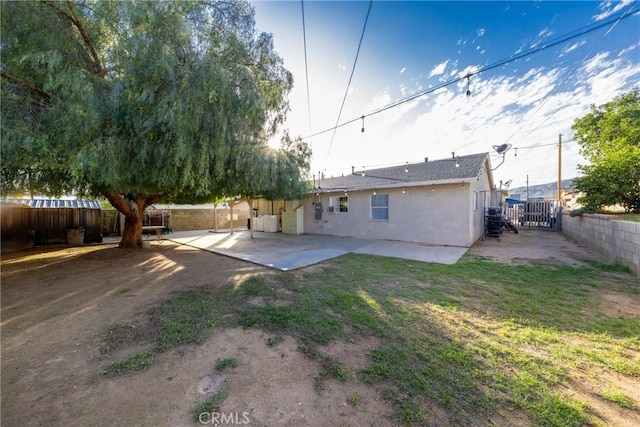 back of house with stucco siding, a fenced backyard, and a patio