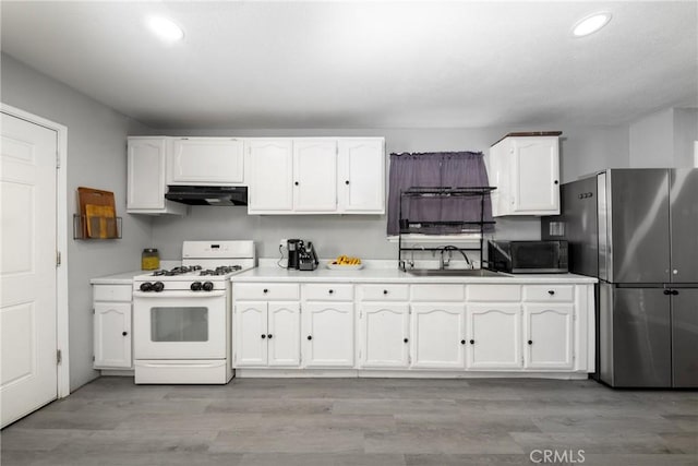 kitchen featuring white gas range oven, white cabinets, light countertops, under cabinet range hood, and a sink