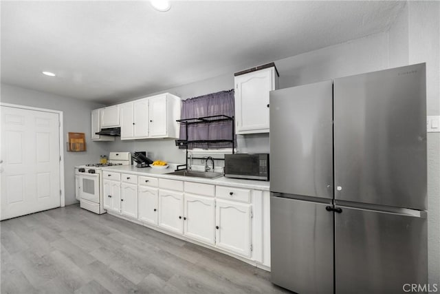 kitchen featuring appliances with stainless steel finishes, white cabinets, and a sink