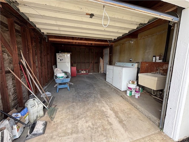 garage featuring independent washer and dryer, a sink, and freestanding refrigerator