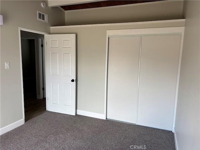 unfurnished bedroom with visible vents, baseboards, vaulted ceiling with beams, carpet, and a closet