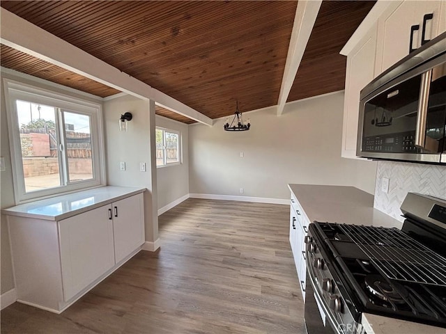 kitchen with tasteful backsplash, appliances with stainless steel finishes, white cabinets, wood finished floors, and beamed ceiling