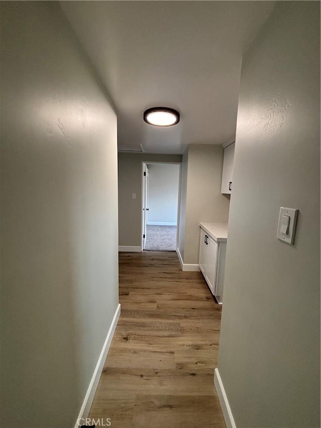 hall featuring light wood-type flooring and baseboards