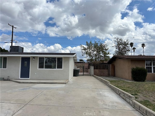 single story home featuring a gate, fence, and stucco siding