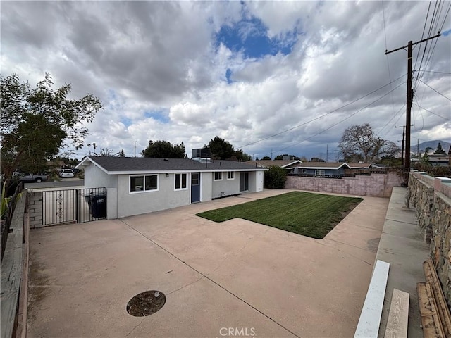 view of front facade featuring a patio area, a fenced backyard, a front lawn, and stucco siding