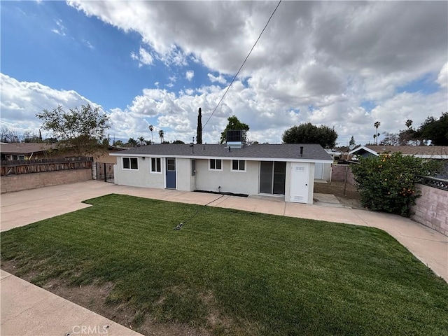 back of house featuring a lawn, a patio area, fence, and stucco siding