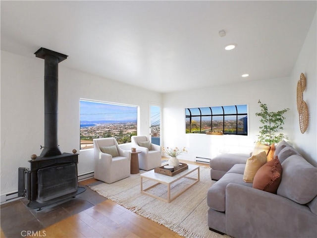 living room with a baseboard heating unit, recessed lighting, a wood stove, and wood finished floors