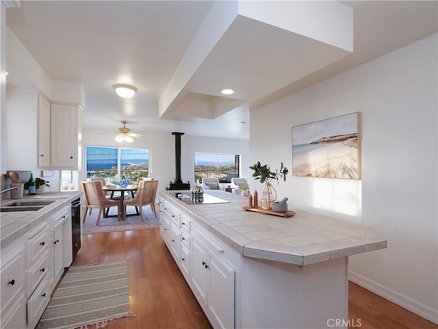 kitchen featuring tile counters, a sink, black appliances, and wood finished floors