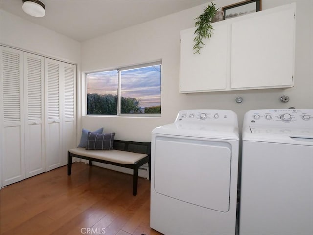 clothes washing area featuring light wood-type flooring, independent washer and dryer, and cabinet space