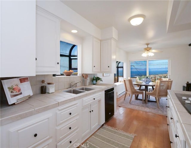 kitchen with light wood-style floors, a sink, tile countertops, and dishwasher