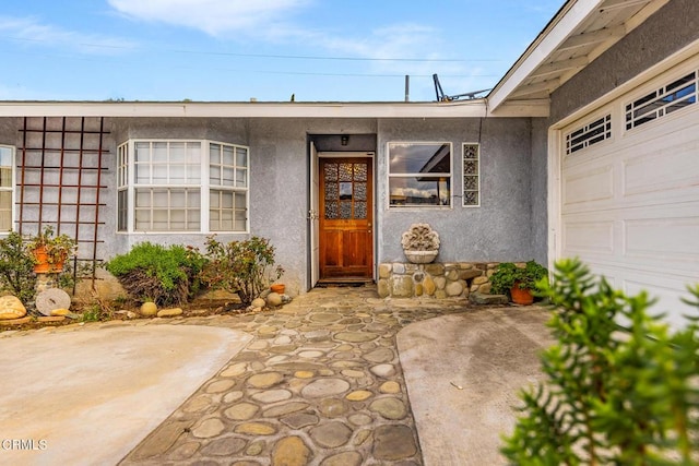 property entrance featuring stucco siding and an attached garage