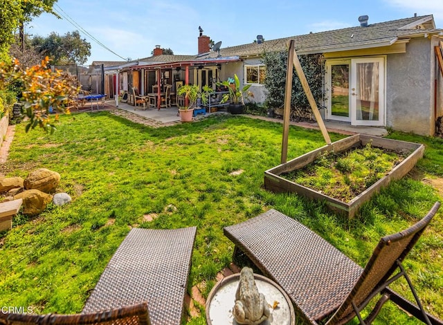 rear view of house with a trampoline, stucco siding, a lawn, a garden, and a patio area